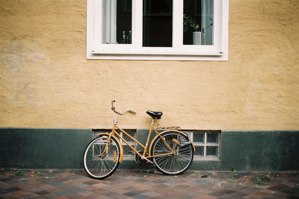 Gold bike propped up against a wall. Porch shares some important tips and tricks on what to consider when thinking about bicycle storage