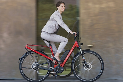 A lady wearing a suit and riding a red bicycle.