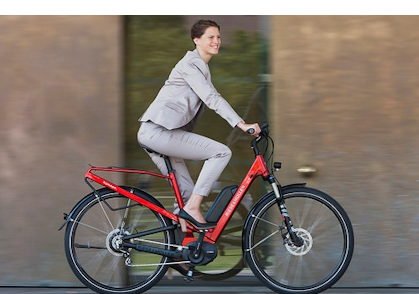 A lady wearing a suit and riding a red bicycle.